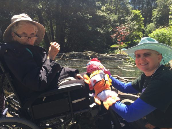 Eileen enjoys a donut; Mary hangs with Fish Puppets at the Koi Pond