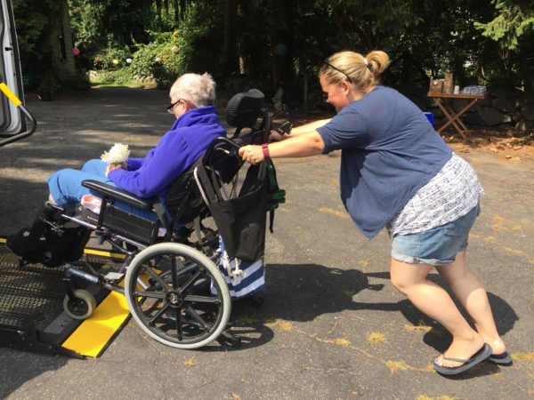 Abi Assists Eileen Onto the Chair Van