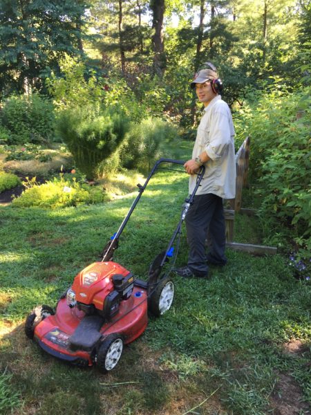 Caleb Bresley, a new horticultural volunteer, mows the grass
