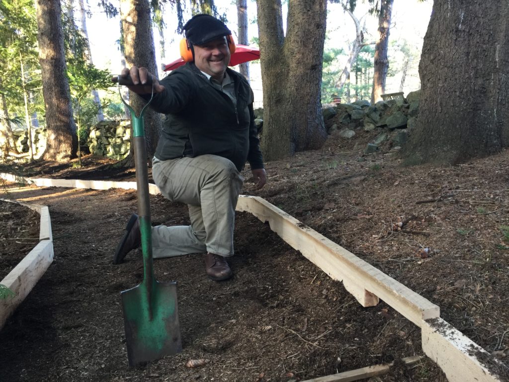 Karl takes notches out of the wood edging to allow room for tree roots